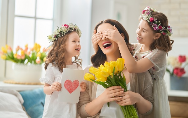 hijas regalando un ramo de flores a su madre