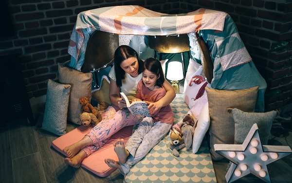 madre e hija leyendo bajo un refugio hecho con sábanas en el comedor