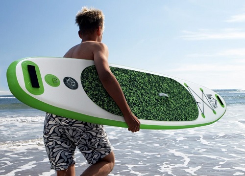 Chico agarrando tabla de pádel surf para entrar al mar