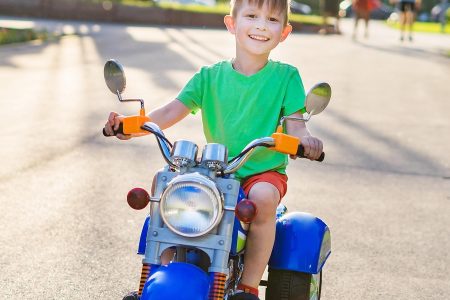 niñe montado sobre una moto eléctrica infantil de color azul