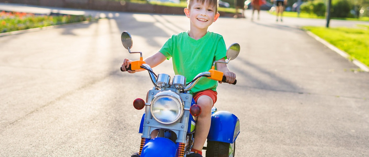 niñe montado sobre una moto eléctrica infantil de color azul