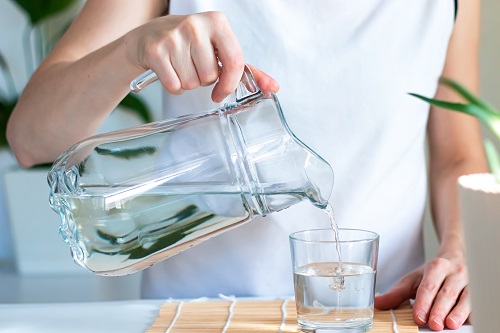 Mujer llenando un vaso de agua con una jarra