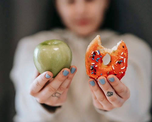 chica mostrando un donut y una manzana