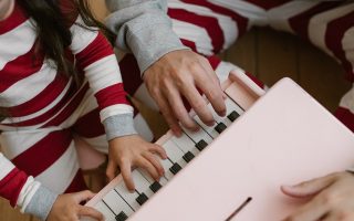 primer plano de una niña tocando un piano infantil de juguete de color rosa