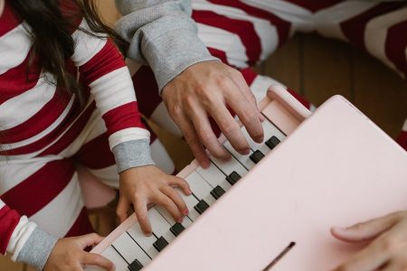 primer plano de una niña tocando un piano infantil de juguete de color rosa