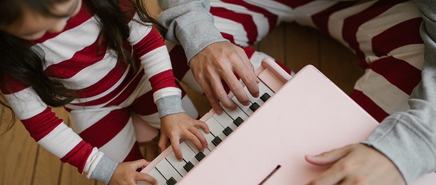 primer plano de una niña tocando un piano infantil de juguete de color rosa