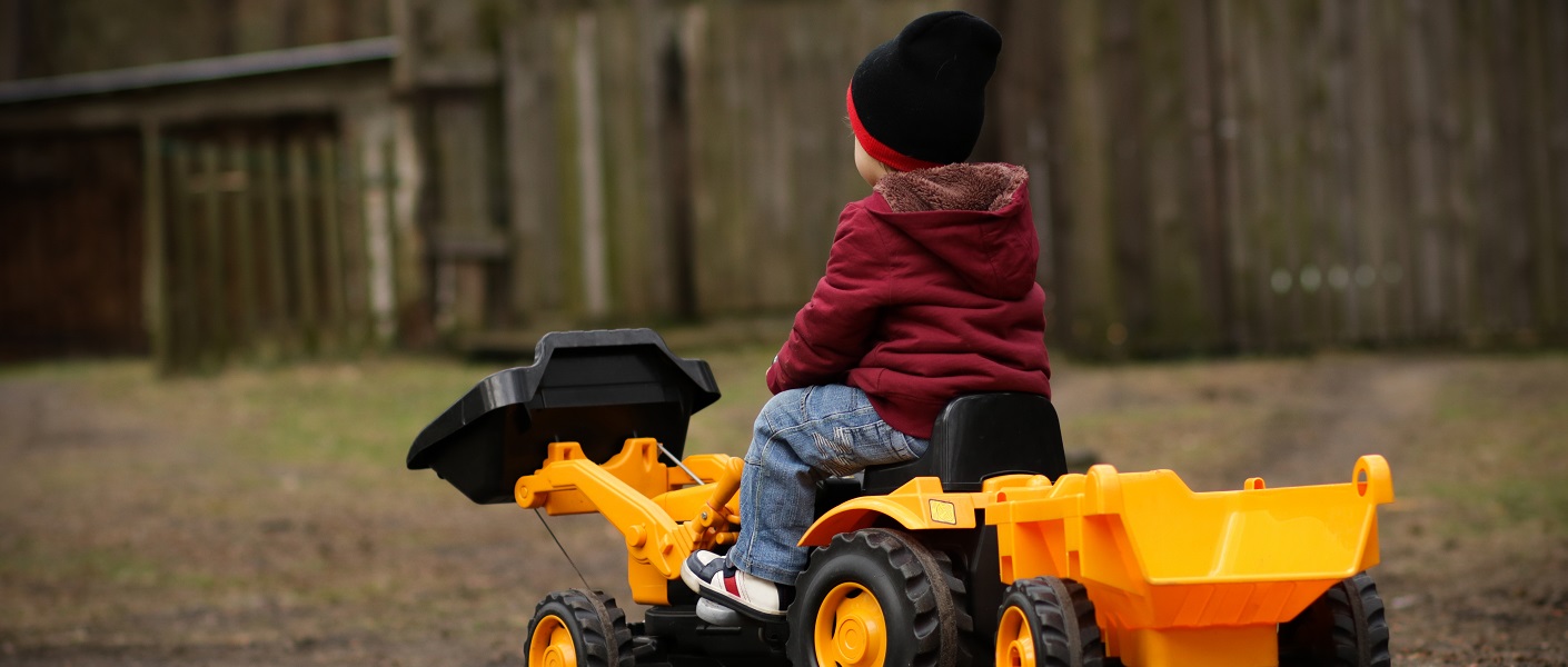 niño con tractor de juguete amarillo