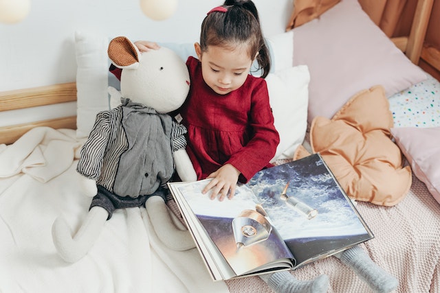 niña leyendo un cuento al lado de su peluche