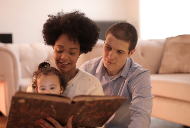 padres leyendo un libro junto a su hijo pequeño