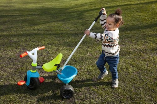 niña con su triciclo con barra de empuje
