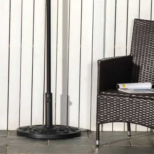 Base semicircular negra con motivo floral apoyada contra pared de madera blanca, las mejores bases de sombrilla para tu terraza o jardín.