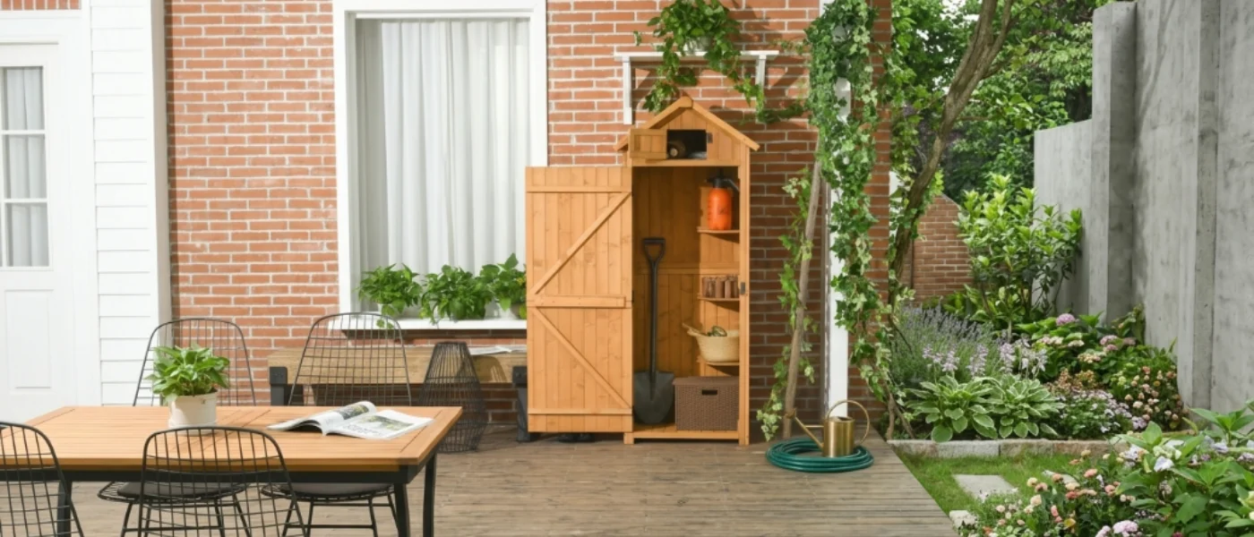 Armario de madera natural tipo cobertizo con puerta abierta junto a una terraza con mesa y sillas