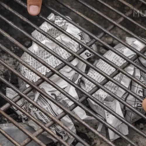 Bolas de papel de periódico bajo la rejilla de la parrilla de carbón