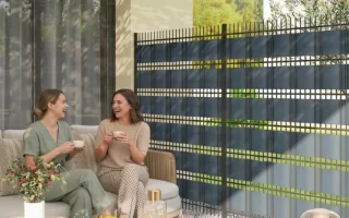 Dos mujeres charlando junto a una valla de privacidad de rejilla