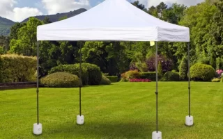 Gazebo blanco fijado con pesos de base en un jardín