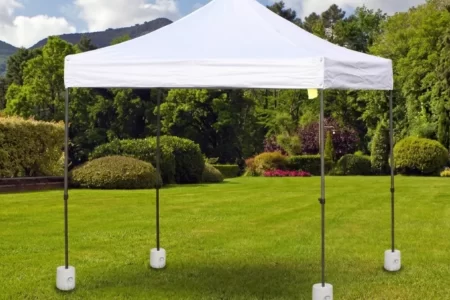 Gazebo blanco fijado con pesos de base en un jardín