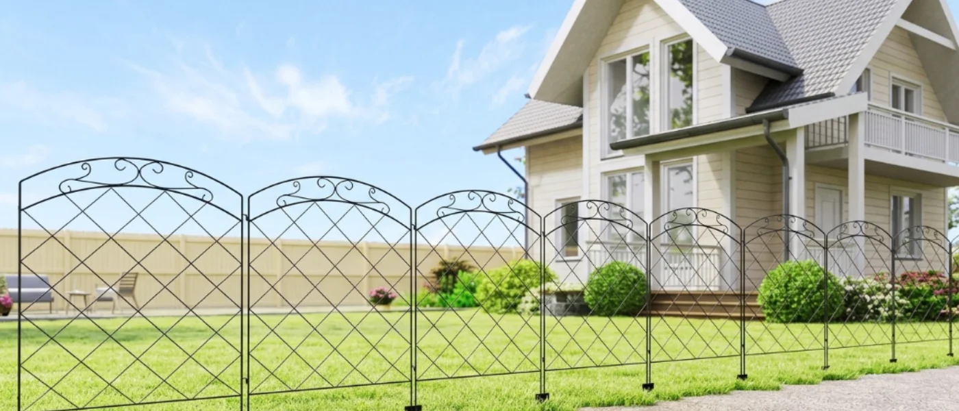 Hilera de paneles de valla decorativos de metal negro con motivo de arco delante de una casa