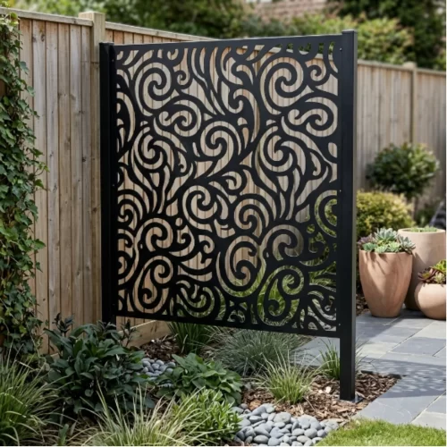 Panel decorativo de metal negro con patrón de espirales colocado delante de una valla de madera