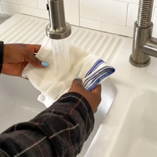 Enjuagando un trapo blanco bajo el grifo del fregadero.