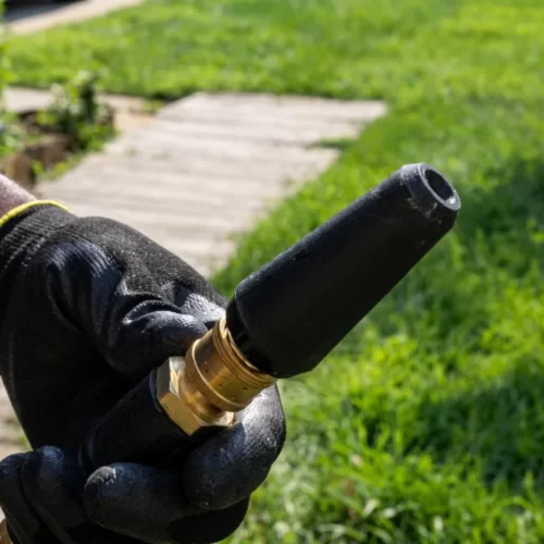 Hidrolimpiadora eléctrica pulverizando una valla de madera, mostrando el chorro de la boquil