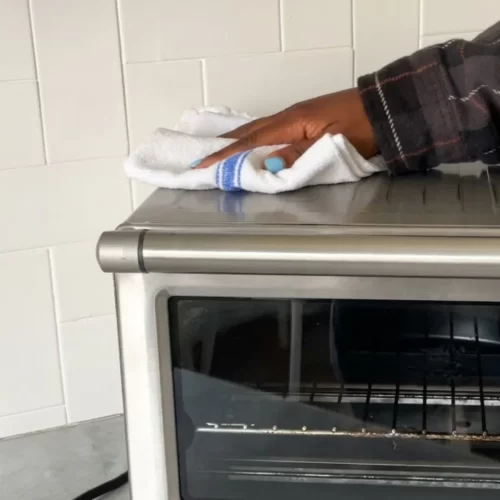 Limpiando la superficie exterior de acero inoxidable del horno tostador.