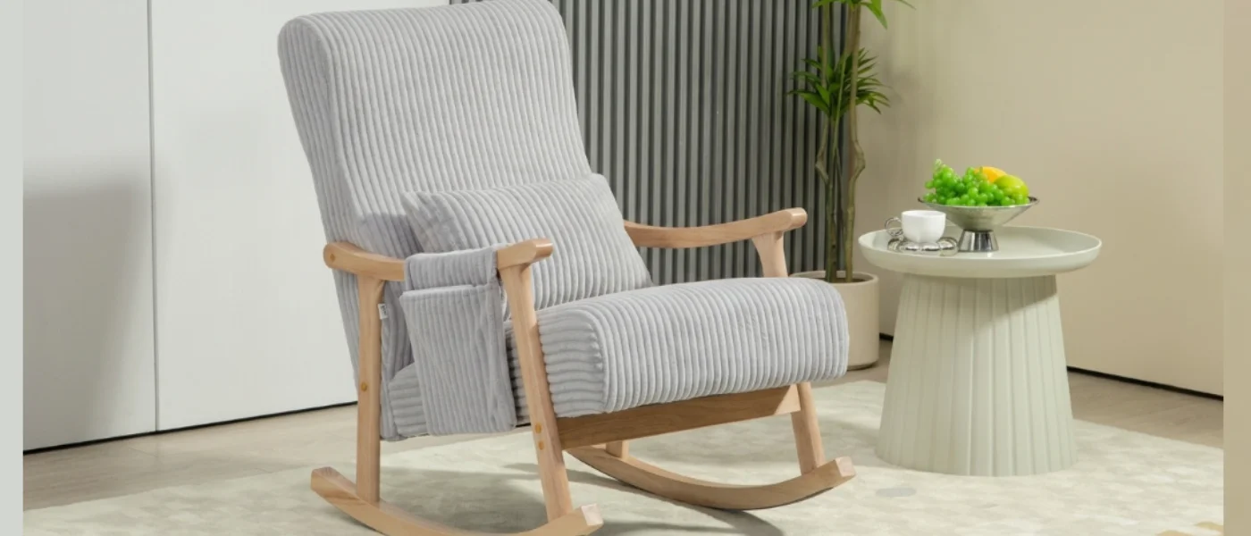 Mecedora tapizada en gris con reposabrazos de madera y cojín lumbar en el saló