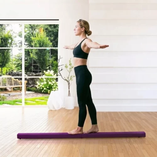 Mujer caminando hacia adelante sobre una barra de equilibrio.