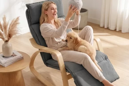 Mujer jugando con su cachorro golden retriever en mecedora de madera y tela gris