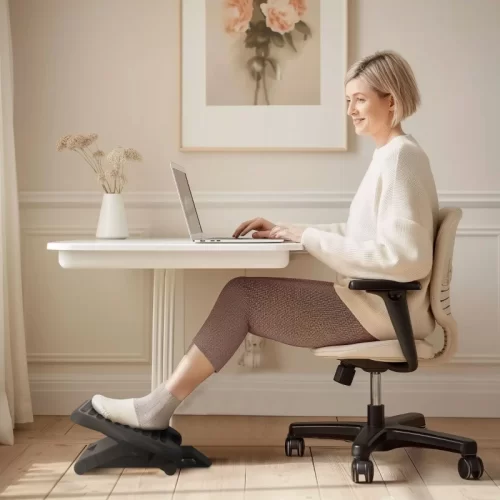 Mujer trabajando con portátil y los pies apoyados en un reposapiés