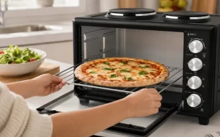 Persona sacando una rejilla con una pizza margarita recién hecha de un mini horno negro con dos placas de cocción encima. 1400