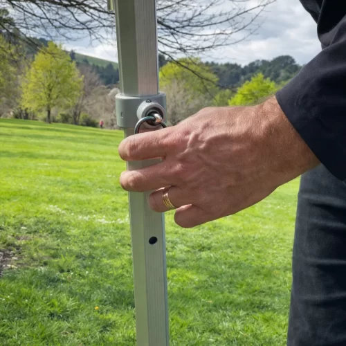 Persona soltando el pasador de ajuste de altura en la pata de una carpa gazebo