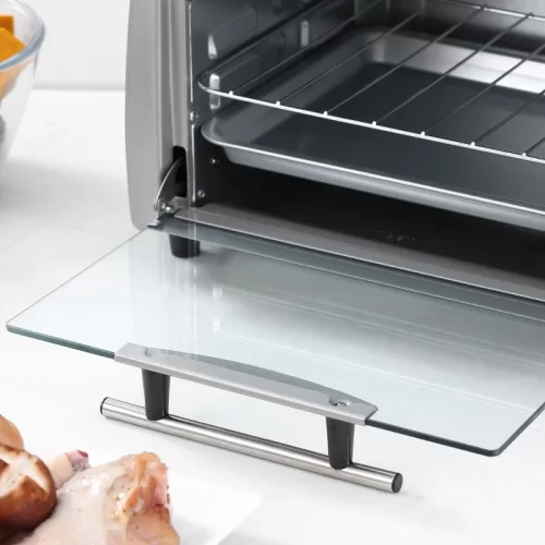 Primer plano de la puerta de cristal abierta de un mini horno con tirador cromado, mostrando la bandeja y la rejilla colocadas dentro.
