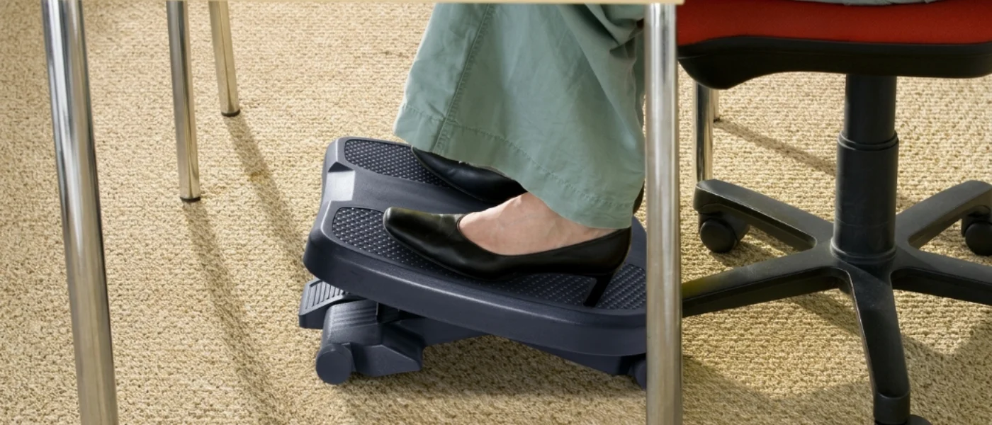 Reposapiés negro bajo un escritorio con zapato de tacón apoyado 1400