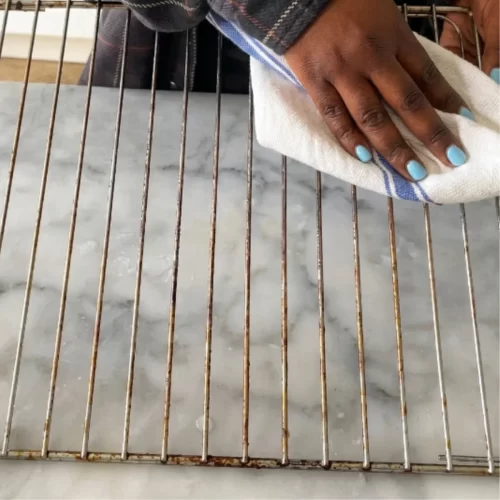 Secando una rejilla metálica limpia con un paño de cocina.