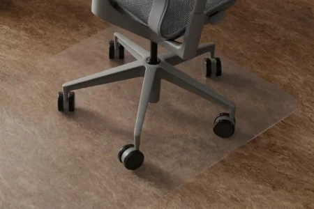 Silla de oficina con ruedas sobre alfombrilla transparente en suelo de piedra