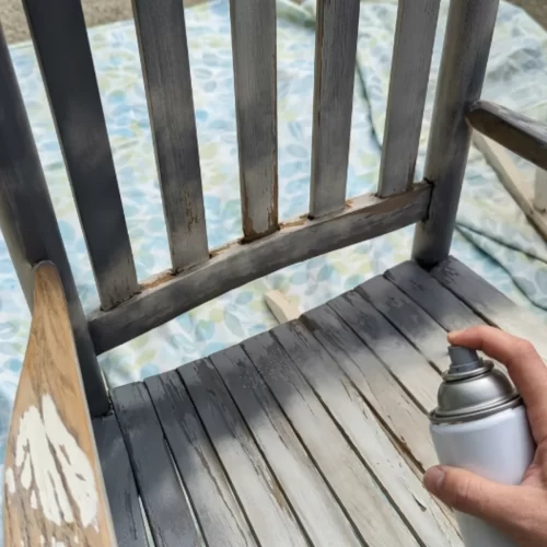 Aplicando imprimación en spray blanco al respaldo de una mecedora