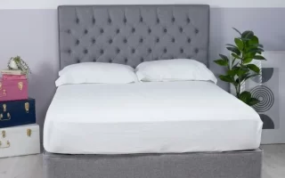 Cama con cabecero tapizado gris ya instalado y ropa de