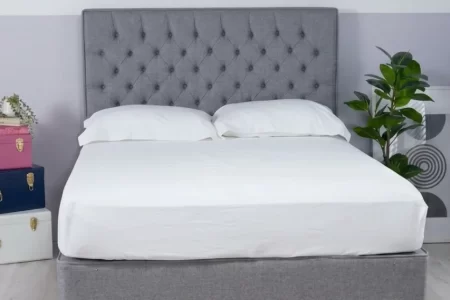 Cama con cabecero tapizado gris ya instalado y ropa de