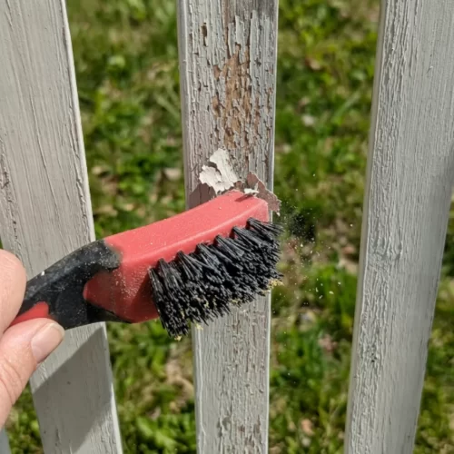 Cepillo de alambre eliminando pintura desconchada de un listón de madera