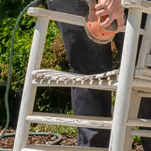 Lijando el asiento de una mecedora de madera con lijadora eléctrica