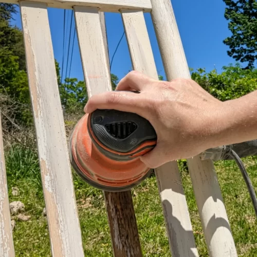 Lijando una valla de madera con lijadora eléctrica al aire libre