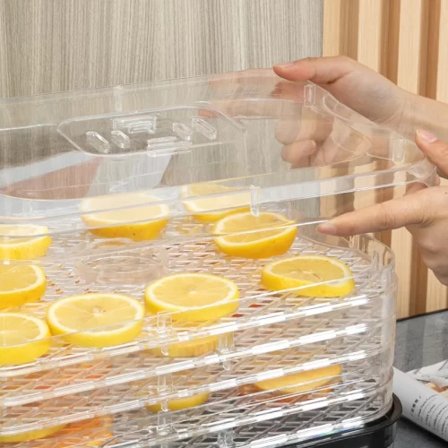 Manos colocando la tapa transparente sobre una bandeja de rodajas de limón deshi