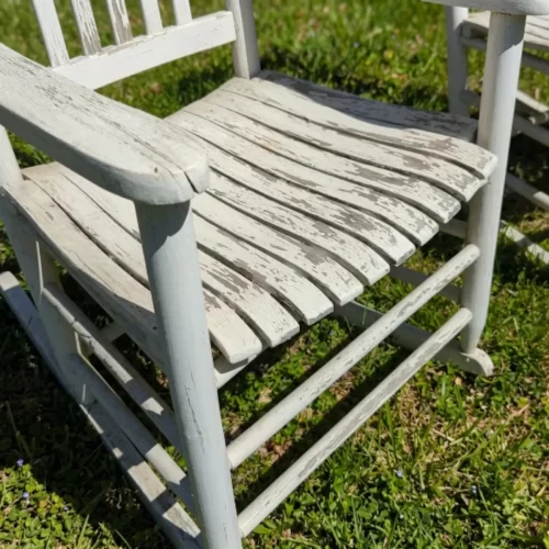 Mecedora blanca con pintura desconchada en el jardín antes de pintar
