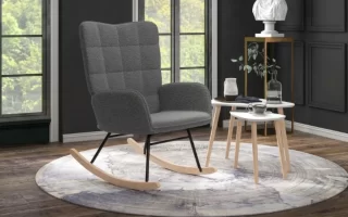 Sillón mecedora gris moderno sobre una alfombra redonda en un salón con suelo de madera