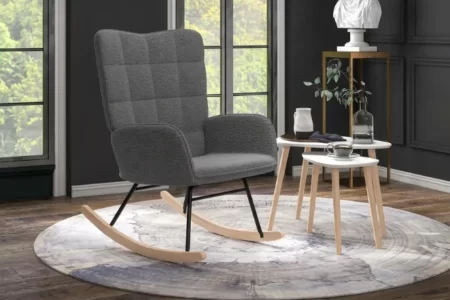 Sillón mecedora gris moderno sobre una alfombra redonda en un salón con suelo de madera