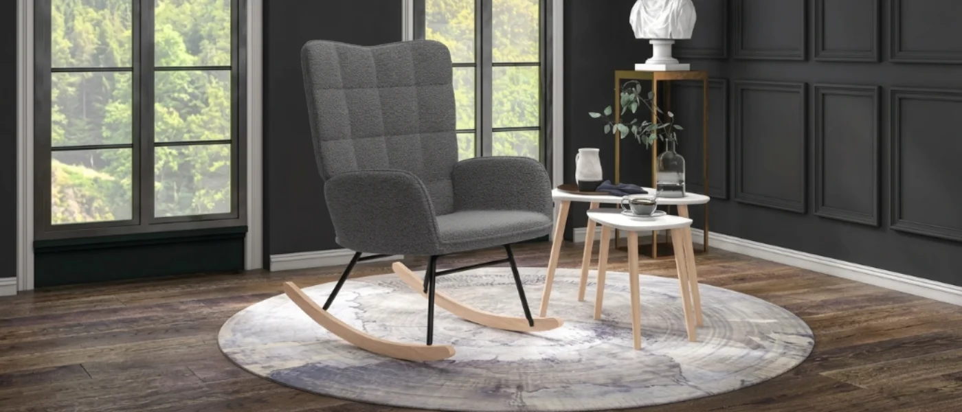 Sillón mecedora gris moderno sobre una alfombra redonda en un salón con suelo de madera