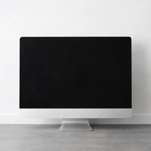 Monitor de computadora apagado sobre mesa frente a pared.