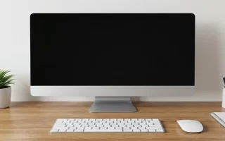Escritorio de madera limpio con monitor, planta y libreta.