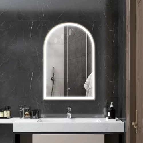 Espejo arqueado iluminado en pared de baño con mármol.